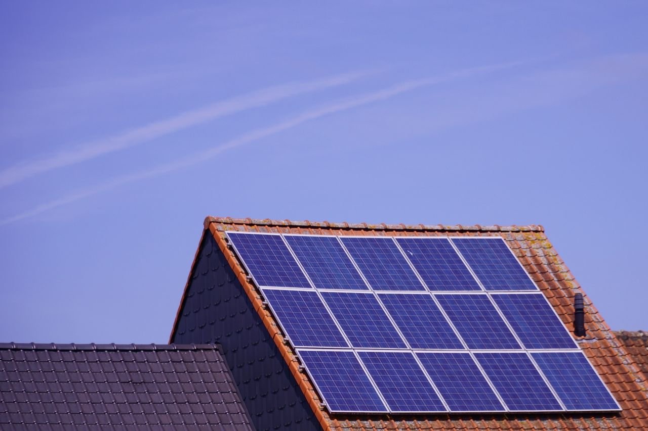 Services Close-up of solar panels on a tiled rooftop under a clear sky, showcasing renewable energy.